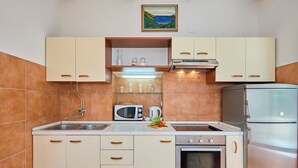 Uma cozinha com micro-ondas, fogão, geladeira e um quadro na parede.