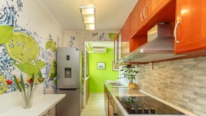 A modern kitchen with a stainless steel refrigerator, wooden cabinets, a white countertop, and a backsplash with a mosaic tile pattern. - Skyscraper Apartment (Dubrovnik)