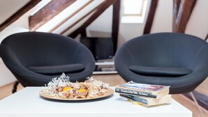 A dining table with a plate of food and books, two black chairs, and a wooden ceiling structure. - Hedera Estate, Hedera A5 Apartment (Dubrovnik)