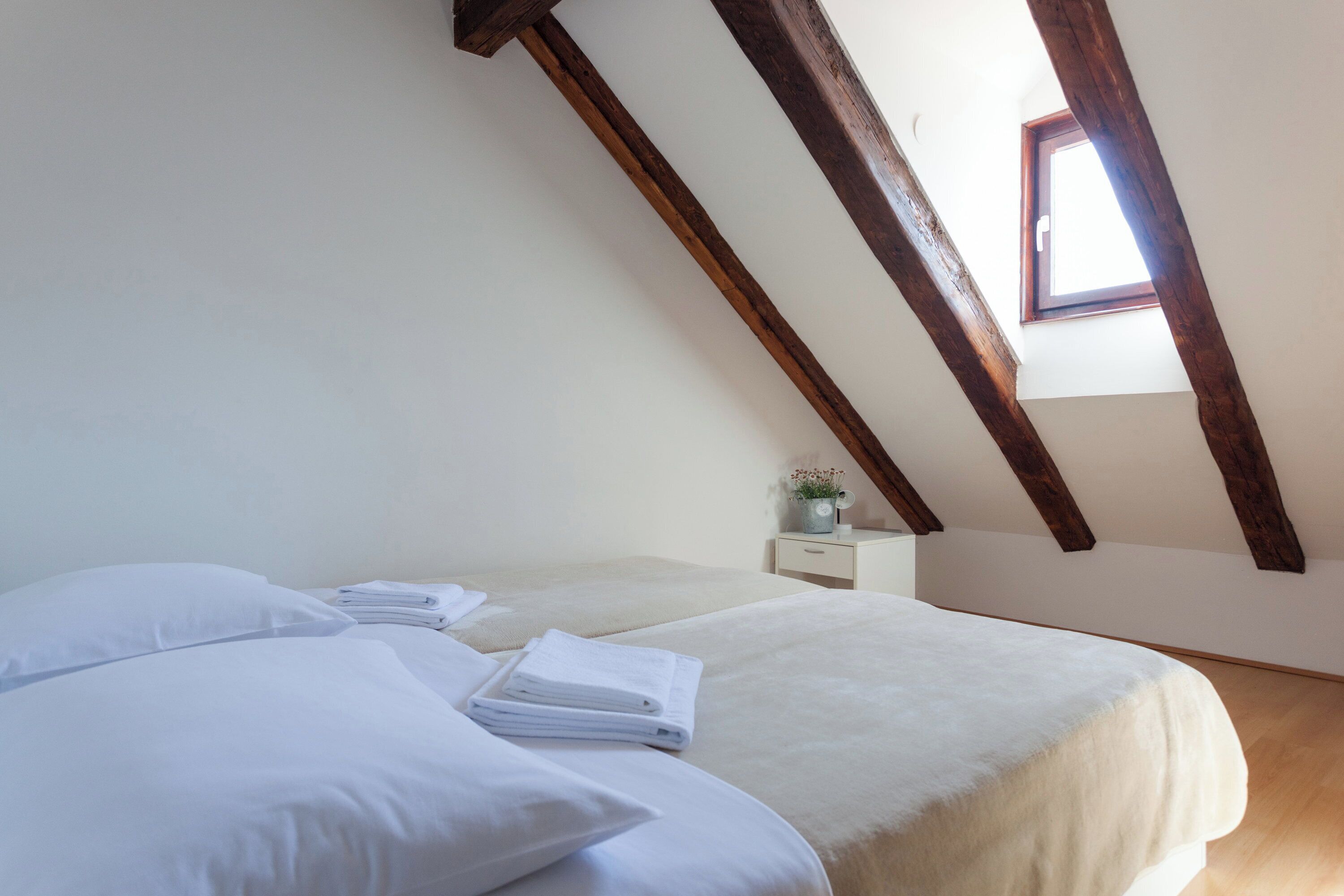 Une chambre à coucher avec un lit, des oreillers, une table de chevet et une fenêtre.