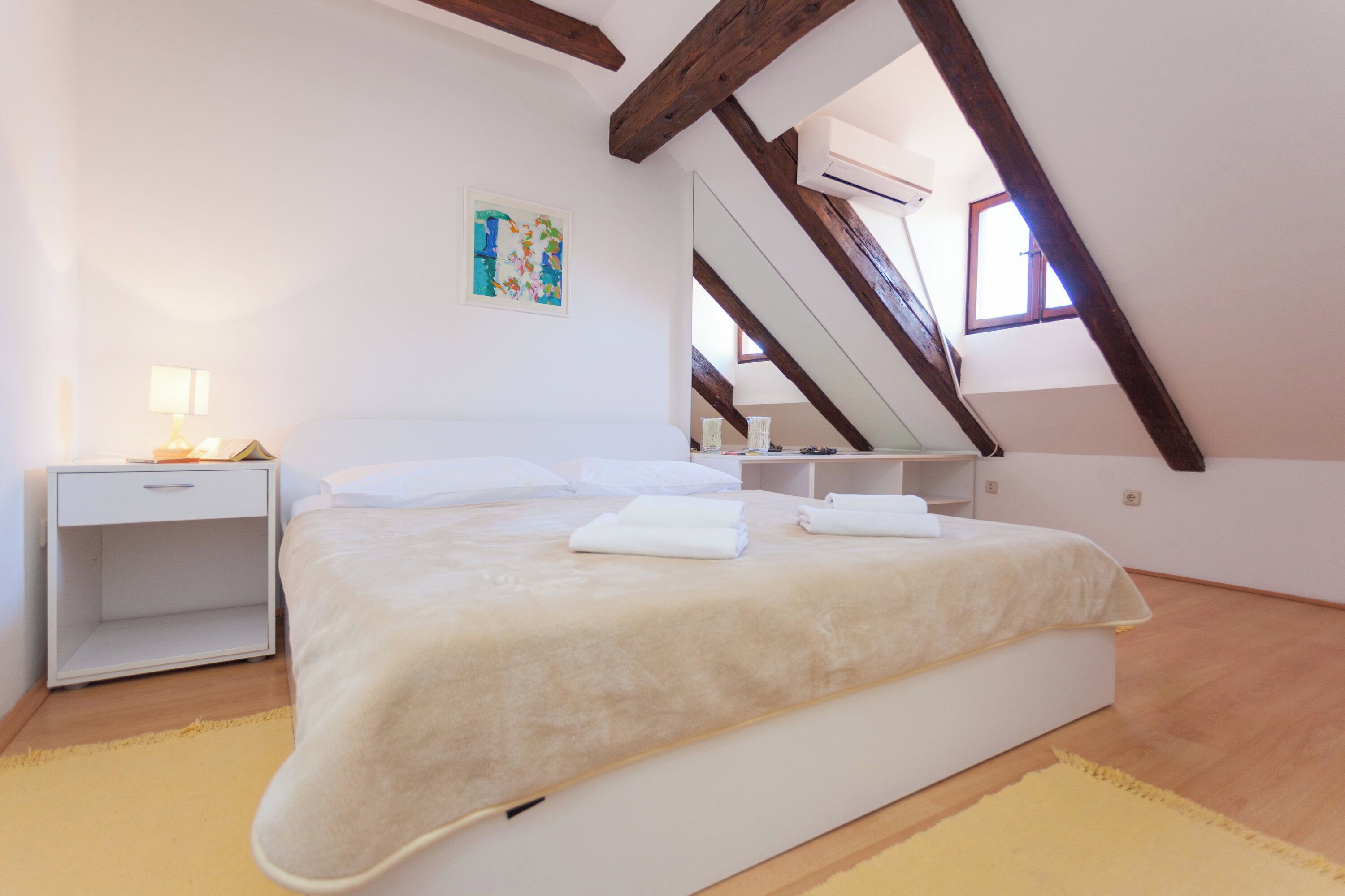 Un dormitorio con cama, mesita de noche y ventana.