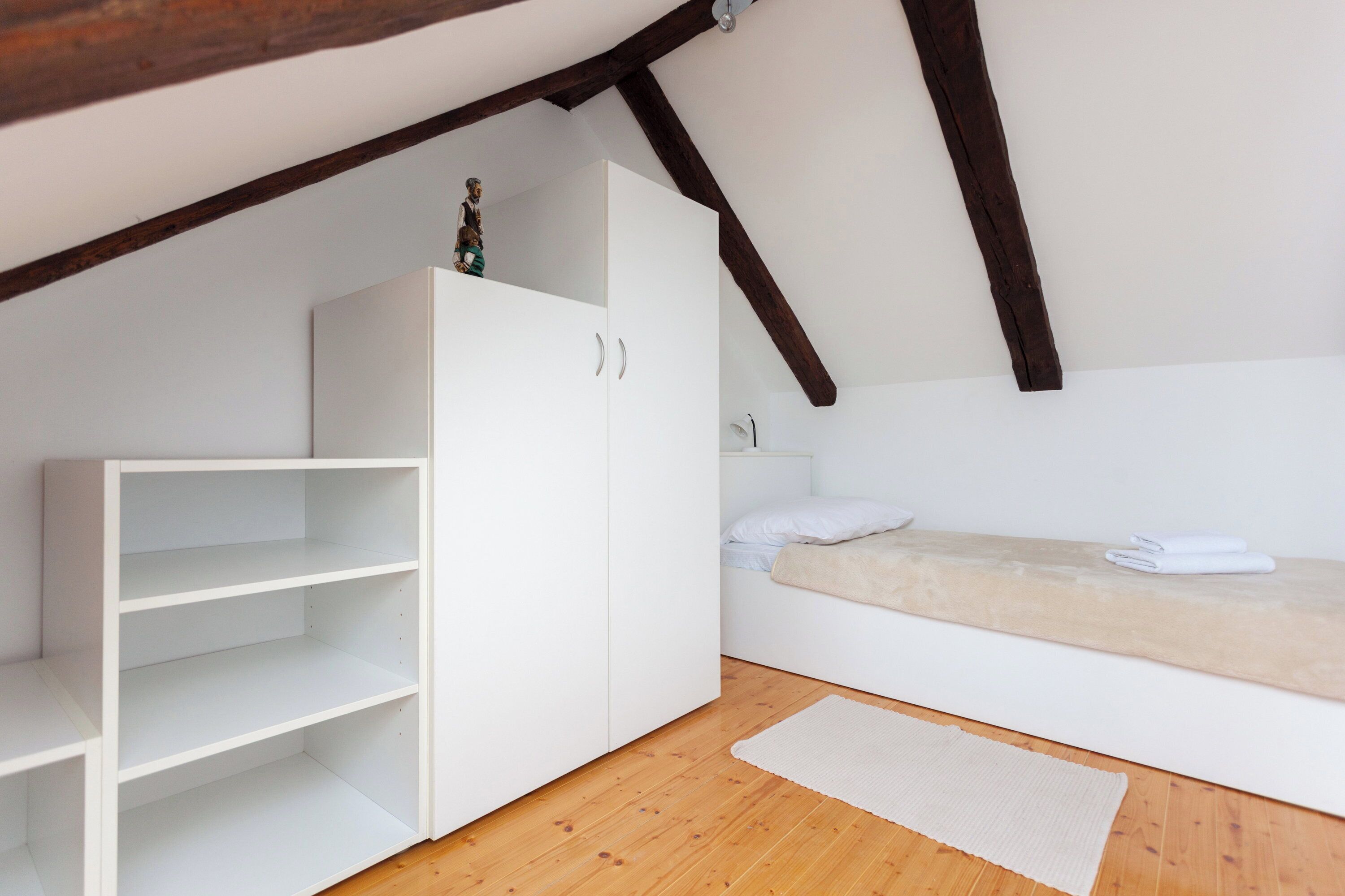 A bedroom with a bunk bed, a white wardrobe, and a wooden floor.