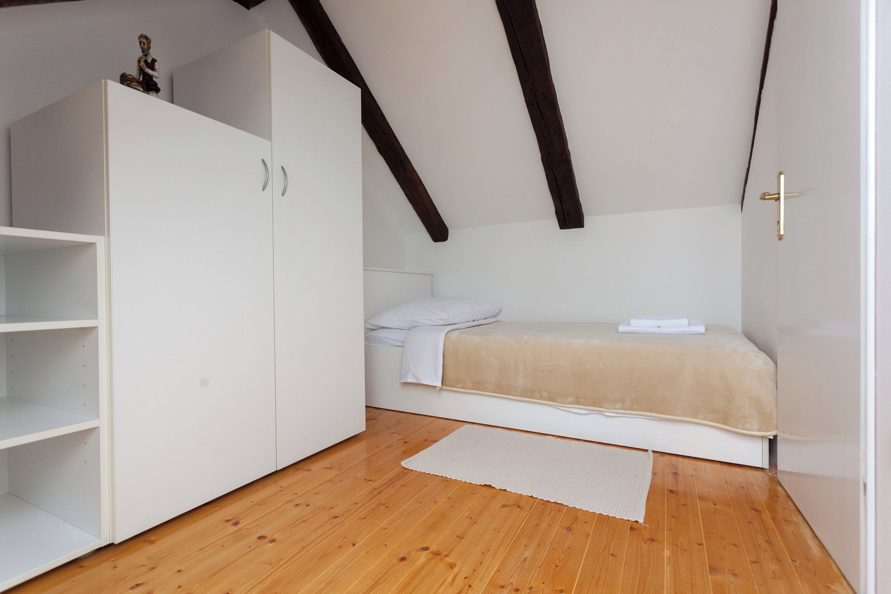 Une chambre à coucher avec un lit, une armoire, une petite table et une porte.