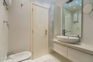 Un bany modern amb una banyera independent, un mirall gran i un lavabo encastrat.