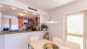 A modern kitchen with stainless steel appliances, a dining area with a white table, and a pendant light. - Hedera Estate, Hedera A14 (Dubrovnik)