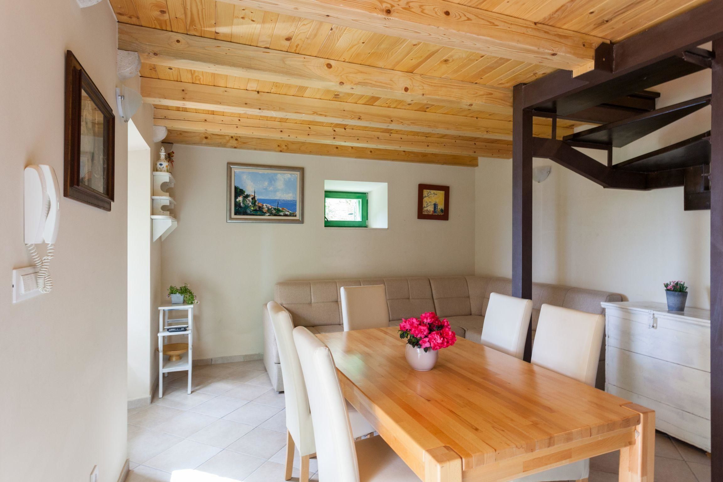Un comedor con mesa y sillas de madera, un sofá y una escalera.