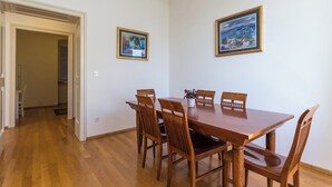 A dining area with a wooden table and chairs, framed pictures on the wall, and a hallway leading to another room. - Hedera Estate, Hedera A27 (Dubrovnik)