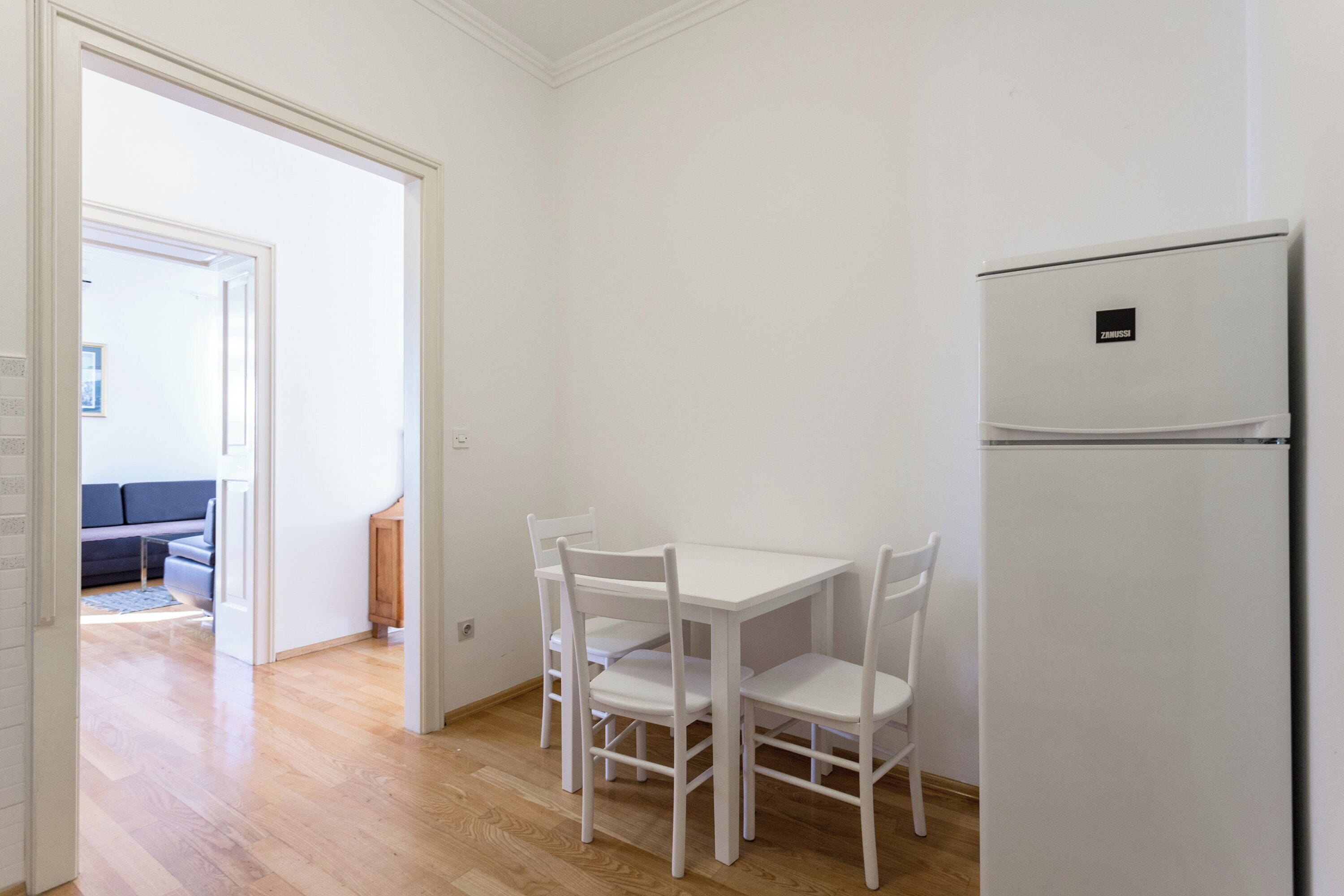 A kitchen with a white refrigerator, a white table, and four white chairs.