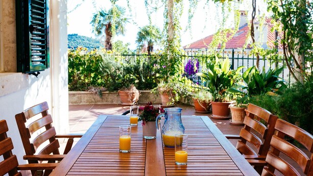 An outdoor patio with a wooden table, chairs, and potted plants. - Hedera Estate, Hedera A27 (Dubrovnik)