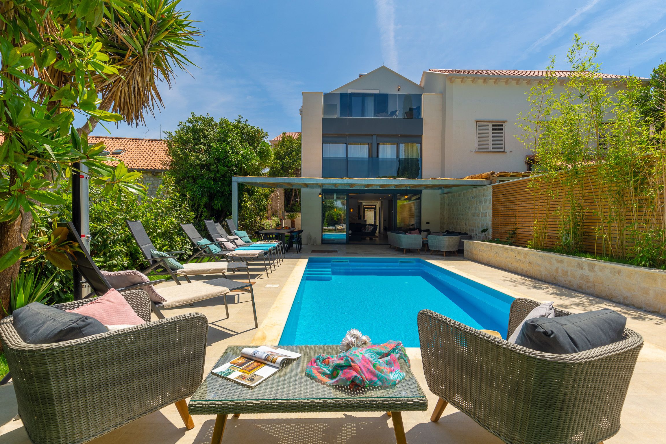 A modern house with a swimming pool, outdoor furniture, and a covered patio area.
