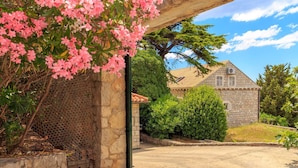 A stone building with a tiled roof, surrounded by greenery and a clear sky. - Hedera Estate, House Hedera V (Dubrovnik)