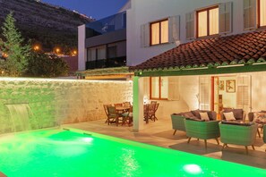 A pool area with a green-lit water feature, outdoor furniture, and a dining set. - Hedera Estate, Villa Hedera (Dubrovnik)