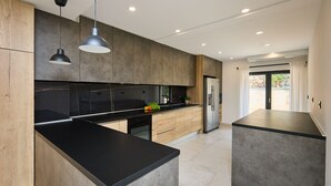 Une cuisine moderne avec des meubles en bois, des plans de travail noirs et des luminaires suspendus.