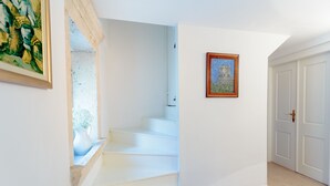 Un escalier menant à un palier où est accrochée une peinture encadrée au mur.