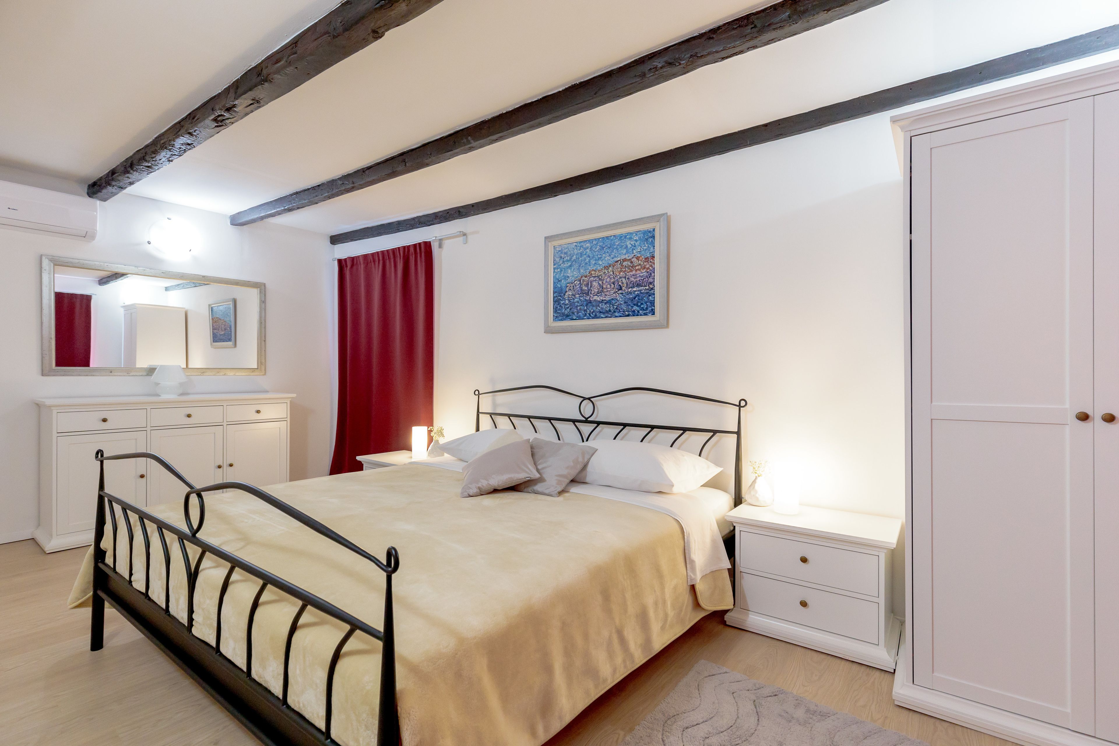 A bedroom with a bed, bedside tables, a wardrobe, and a mirror.