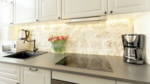 A kitchen with white cabinets, a built-in microwave, a coffee maker, and a vase with flowers on the counter. - Hedera Estate, Hedera A2 Apartment (Dubrovnik)