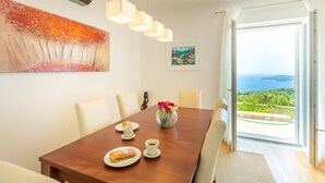 Un comedor con una mesa de madera, sillas, un florero con flores y un cuadro en la pared.