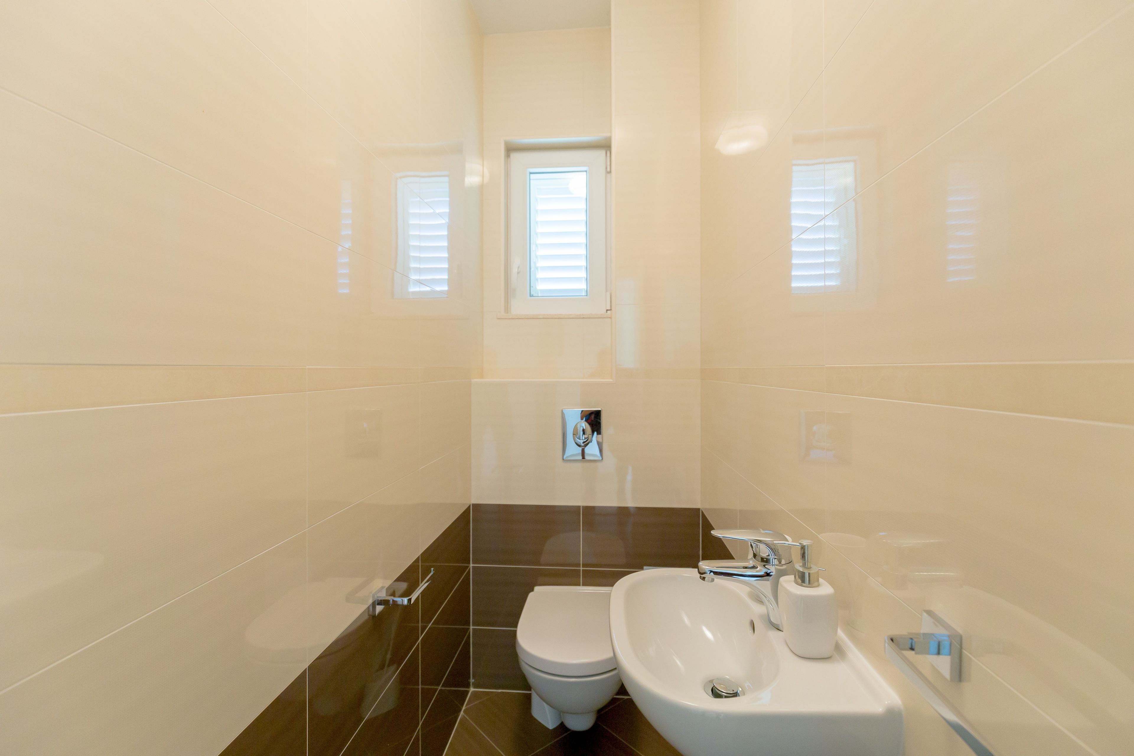 A modern bathroom with a toilet, sink, and window.