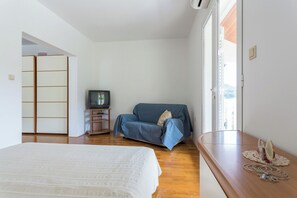 Ein Schlafzimmer mit einem Bett, einem blauen Sofa, einem Fernseher und einer Holzkommode.