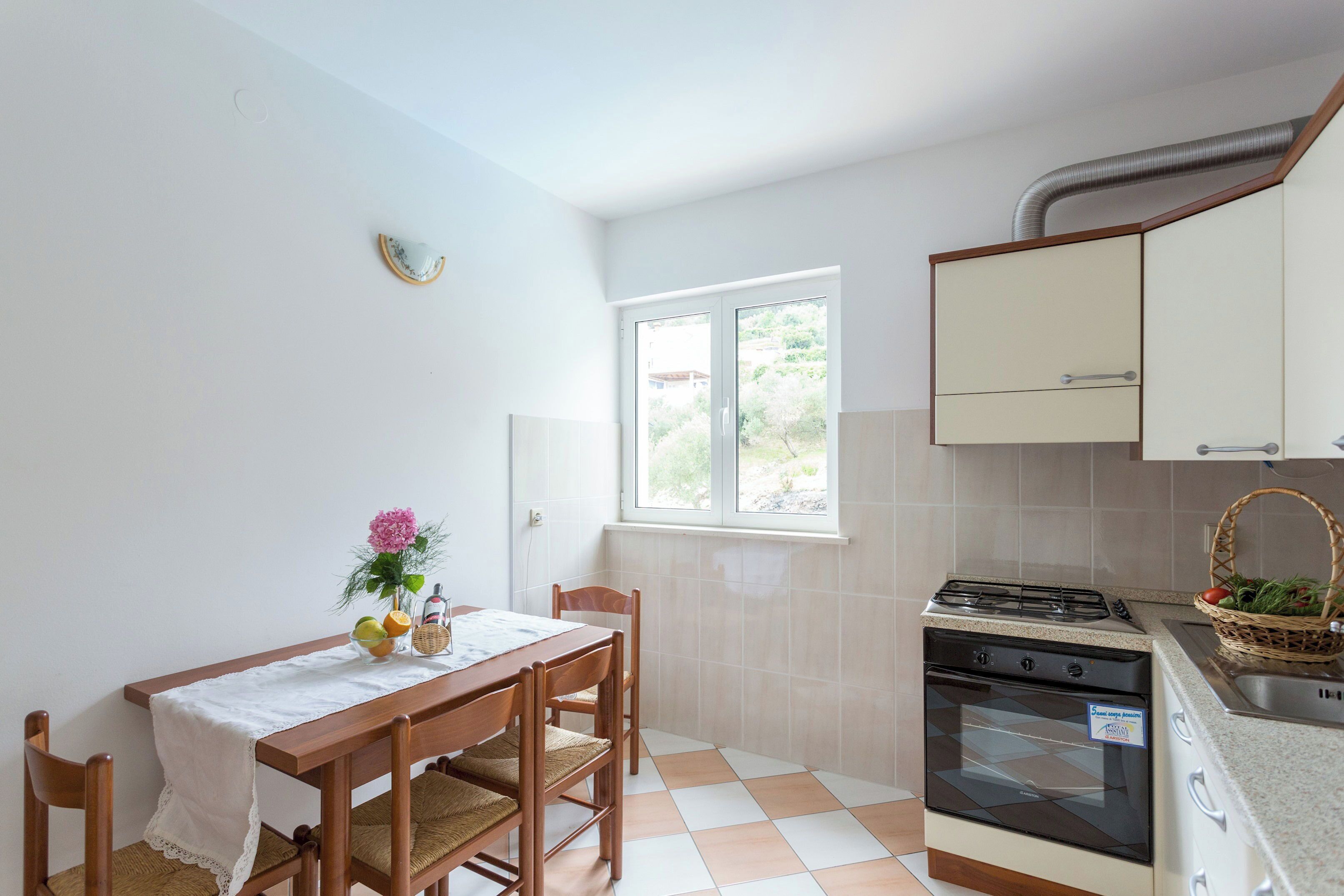 Una cocina con una mesa de comedor, sillas, una ventana, una estufa y armarios.