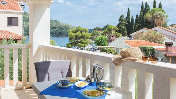 A balcony with a table set for two, a view of the sea, and a row of houses in the background. - Villa Florence - Mediterranean Garden&pool (Dubrovnik)