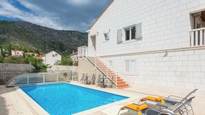 A swimming pool with lounge chairs, a staircase, and a white building with shutters. - Villa Florence - Mediterranean Garden&pool (Dubrovnik)