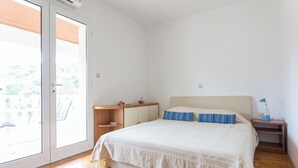 A bedroom with a bed, a nightstand, a desk, and a sliding glass door to the outside. - Villa Florence - Mediterranean Garden&pool (Dubrovnik)