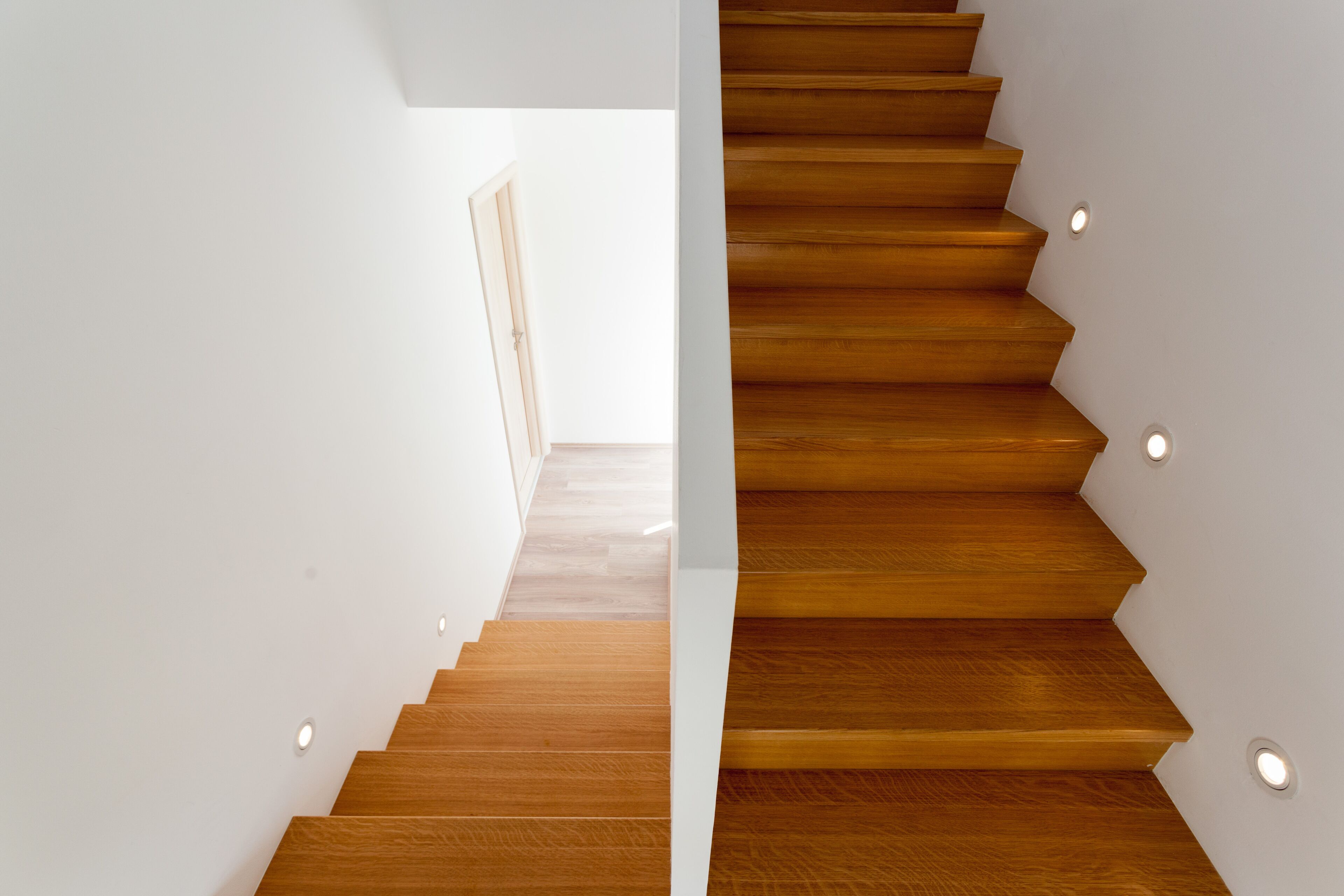 Un escalier moderne avec des marches en bois et un éclairage encastré.