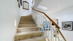 A staircase with a wooden handrail and beige carpeted steps. - Villa Donna Paola (Dubrovnik)