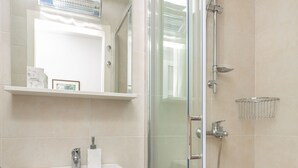 A modern bathroom with a glass shower enclosure, a white sink, and a mirror above the sink. - Apartment Colette (Dubrovnik)
