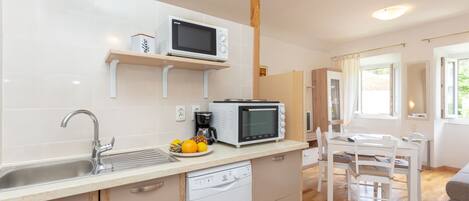 A modern kitchen with white cabinetry, a built-in dishwasher, a microwave, and a coffee machine.