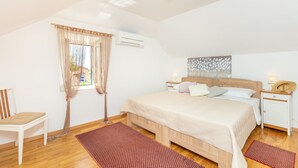 Une chambre à coucher avec un lit, une chaise, une table de chevet et une fenêtre avec des rideaux.