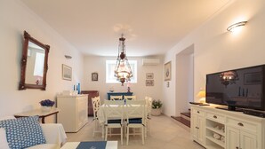 A well-lit living room with a dining area, a TV, and a chandelier. - Hedera Estate, Villa Hedera XI (Dubrovnik)
