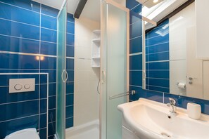 Bathroom features a glass-enclosed shower, white sink, and chrome faucet.