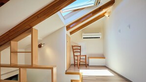 A room with a sloped ceiling, wooden beams, an air conditioning unit, and a chair. - Hedera Estate, Hedera A20 Apartment (Dubrovnik)