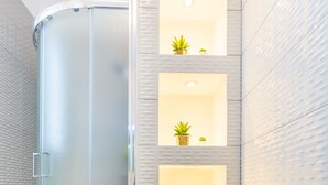 A modern bathroom with a glass-enclosed shower, a textured wall with built-in shelves, and a small potted plant. - Hedera Estate, Villa Hedera V (Dubrovnik)