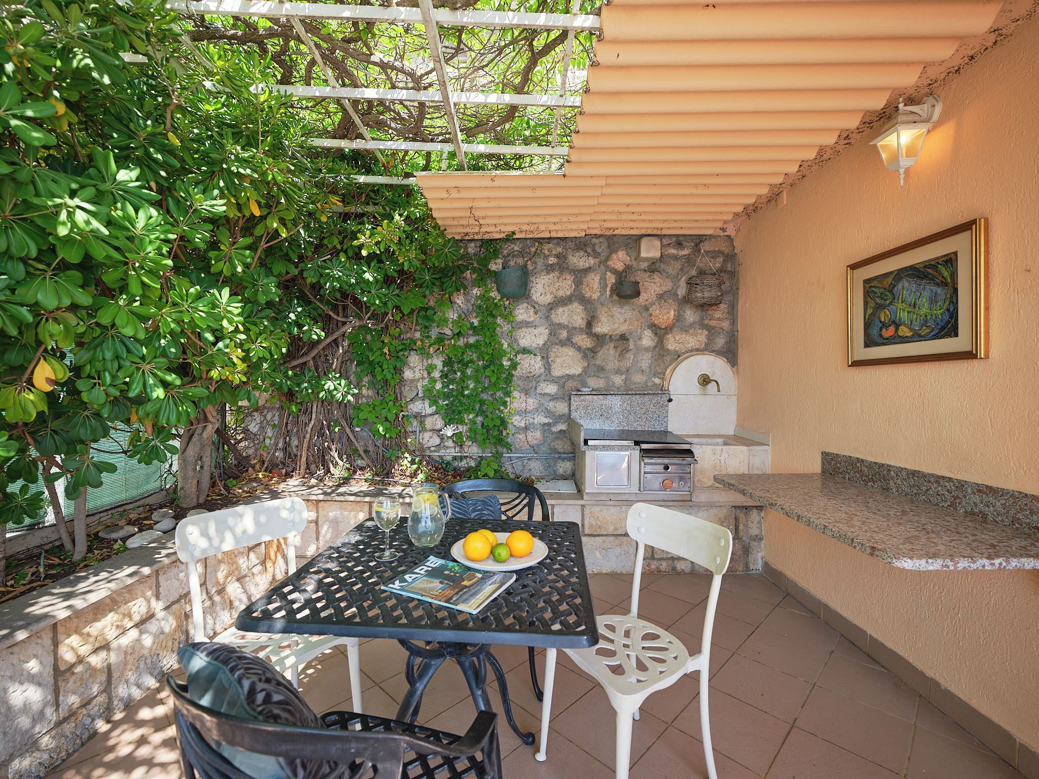 Un patio exterior con una mesa, sillas, una parrilla y un muro de piedra.