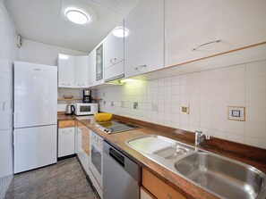 A compact kitchen with white cabinets, a microwave, a coffee maker, and a sink.