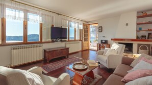 A spacious living room with a large window, a television, a fireplace, and a bookshelf. - Hedera Estate, Hedera A17 (Dubrovnik)