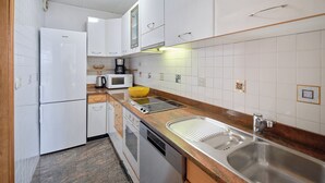 A compact kitchen with white cabinets, a built-in microwave, a coffee maker, and a stainless steel sink. - Hedera Estate, Hedera A17 (Dubrovnik)