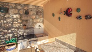 A stone wall with a stone sink, a green watering can, and a blue and white bowl. - Hedera Estate, Hedera A17 (Dubrovnik)
