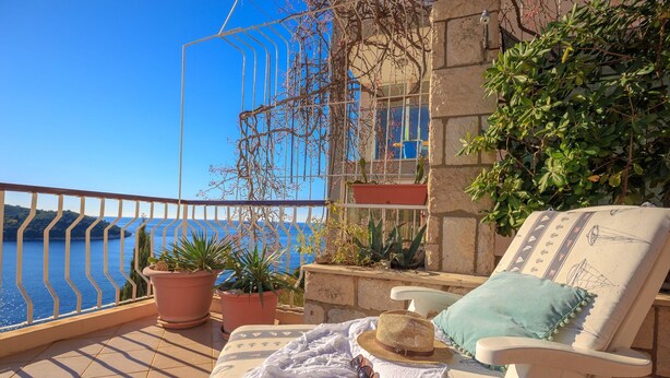 A balcony with a view of the sea, a lounge chair, a sun lounger, and potted plants. - Hedera Estate, Hedera A17 (Dubrovnik)