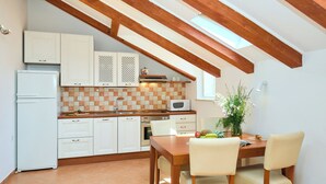 A kitchen with white cabinets, a microwave, a sink, and a dining area with a table and chairs. - Hedera Estate, Hedera A34 (Dubrovnik)