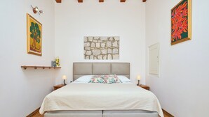 A bedroom with a bed, a stone wall, and two paintings. - Hedera Estate, Hedera A34 (Dubrovnik)