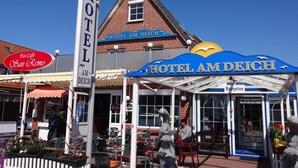 Un hotel con un letrero grande que dice "HOTEL AM DEICH" y un letrero más pequeño para "Eis Cafe San Remo".