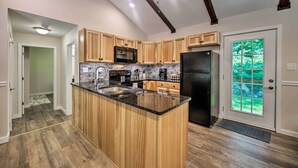 A modern kitchen with wooden cabinets, a granite countertop, and built-in appliances. - Hike, Hunt & Unwind: Cozy Cabin Near Hersheypark (Jonestown)
