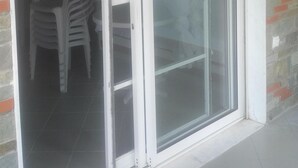Une porte-fenêtre coulissante donnant sur un patio aménagé avec une table et des chaises.