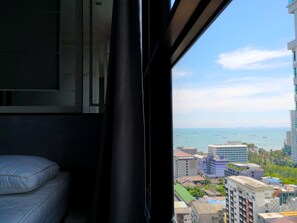 A room with a large window overlooking a cityscape with buildings and a body of water.