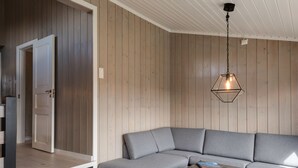 A modern living room with a sectional sofa, a wooden coffee table, and a hanging light fixture.