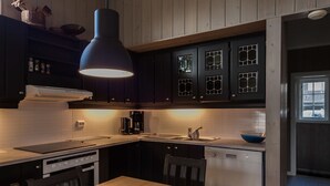 A modern kitchen with dark wooden cabinets, a stainless steel range, and a blue pendant light.